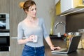Beautiful young woman using her laptop in the kitchen at home. Royalty Free Stock Photo