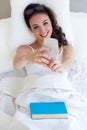 Beautiful young woman using her mobile phone in the bed. Royalty Free Stock Photo