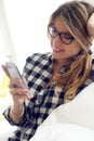 Beautiful young woman using her mobile phone at home. Royalty Free Stock Photo