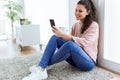 Beautiful young woman using her mobile phone at home.