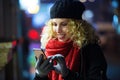 Beautiful young woman using her mobile phone in the street at night. Royalty Free Stock Photo