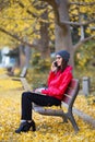 Beautiful young woman using her mobile phone while working with laptop in autumn. Royalty Free Stock Photo