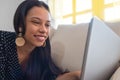 Beautiful young woman is using a laptop and smiling while sitting on the sofa at home Royalty Free Stock Photo