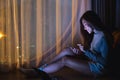 A beautiful young woman using mobile phone and laptop computer with bright light screen in the late night at home Royalty Free Stock Photo