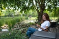 A beautiful young woman using mobile phone with laptop computer on the table in the park Royalty Free Stock Photo