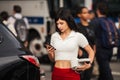 Beautiful young woman using mobile phone near her car on city street. Royalty Free Stock Photo