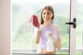 Beautiful young woman is using a rag while cleaning windows Royalty Free Stock Photo