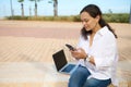 Beautiful young woman using smartphone outdoors, typing text on touch screen. Smart student chatting online with friends Royalty Free Stock Photo