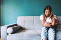 Beautiful young woman using smartphone while relaxing on sofa at living room Royalty Free Stock Photo