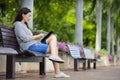 Beautiful young woman using tablet computer on a bench in the park Royalty Free Stock Photo