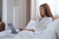 A beautiful young woman using and working on laptop computer while lying on bed at home Royalty Free Stock Photo