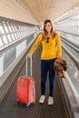 Beautiful young woman very happy walking on the treadmill at the airport with her luggage. Royalty Free Stock Photo