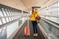 Beautiful young woman very happy walking on the treadmill at the airport with her luggage.