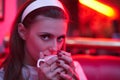 Beautiful young woman in vintage dress in red light cafe drinking coffee Royalty Free Stock Photo