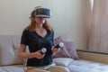 Beautiful young woman with virtual reality headset and joysticks playing video games home Royalty Free Stock Photo