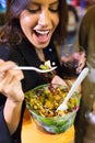 Beautiful young woman visiting eat market and eating colorful salad in the street. Royalty Free Stock Photo