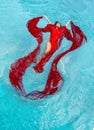 Beautiful young woman with vitiligo disease in red dress, evening dress floating weightlessly elegant in the water in the pool Royalty Free Stock Photo