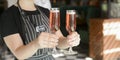 Beautiful young woman waiter serving two glasses of champagne in restaurant, cafe or bar. Bartender at work. Royalty Free Stock Photo