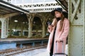 Beautiful young woman waiting for train at train station for travel in autumn. Royalty Free Stock Photo