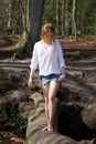 Beautiful young woman walking across a log over stream Royalty Free Stock Photo