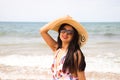 Beautiful young woman walking along the beach with a hat to protect herself from the sun. The woman is enjoying her trip to a Royalty Free Stock Photo