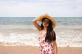 Beautiful young woman walking along the beach with a hat to protect herself from the sun. The woman is enjoying her trip to a Royalty Free Stock Photo