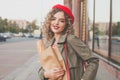 Beautiful young woman walking along city street. Portrait of nice young woman wearing a trench coat, looking at camera and smiling Royalty Free Stock Photo