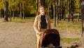 Beautiful young woman walking with baby stroller at autumn park. Parenting, relaxing outdoors, beautiful mother Royalty Free Stock Photo