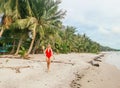 Beautiful young woman walking on the beach along palm trees holding coconut in Koh Phangan, Thailand Royalty Free Stock Photo