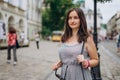 Beautiful young woman walking through the old city. Brunette girl in dress with handbag and glasses. Woman and city in summer