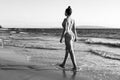 Beautiful young woman walking in sea on sandy beach. Summer travel. Summer beach and sea. Royalty Free Stock Photo