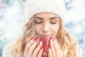 Beautiful young woman in warm clothing with cup of hot tea coffee or punch. Portrait in abstract winter snowy weather Royalty Free Stock Photo