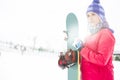 Beautiful young woman in warm clothing holding snowboard during winter Royalty Free Stock Photo