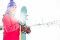 Beautiful young woman in warm clothing holding snowboard during winter Royalty Free Stock Photo