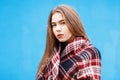 Beautiful young woman in a warm scarf near a blue wall