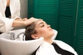 Beautiful young girl washes her head in a beauty studio. Hairdresser is washing hair for client Royalty Free Stock Photo