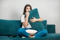 Beautiful young woman watching scary movie on the sofa eating popcorn on the sofa at home looking frightened holding Royalty Free Stock Photo