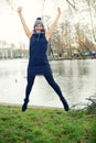 Young woman by the water jumping in the air Royalty Free Stock Photo