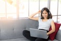 Beautiful young woman wear headphones and using laptop while sitting on sofa at home, work from home, conference meeting Royalty Free Stock Photo