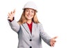 Beautiful young woman wearing architect hardhat looking at the camera smiling with open arms for hug Royalty Free Stock Photo