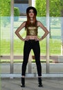 Beautiful young woman wearing black hat, gold top and black jeans modeling. Nineteen`s style. Fashion photo shoot. Royalty Free Stock Photo