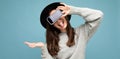 beautiful young woman wearing black hat and grey sweater holding phone showing smartphone showing tongue isolated on Royalty Free Stock Photo