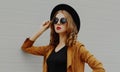 beautiful young woman wearing a black round hat, brown jacket on a gray background Royalty Free Stock Photo