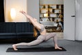 Beautiful young woman wearing brown sportswear practicing yoga, standing in Warrior one pose. Attractive girl working out at home Royalty Free Stock Photo