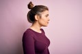 Beautiful young woman wearing casual bun hairstyle over pink isolated background looking to side, relax profile pose with natural Royalty Free Stock Photo