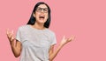 Beautiful young woman wearing casual clothes and glasses crazy and mad shouting and yelling with aggressive expression and arms Royalty Free Stock Photo