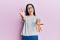 Beautiful young woman wearing casual clothes and glasses looking at the camera smiling with open arms for hug Royalty Free Stock Photo