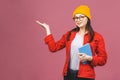 Beautiful young woman wearing casual and eyeglasses standing isolated over pink background, pointing finger, reading a book