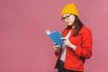 Beautiful young woman wearing casual and eyeglasses standing isolated over pink background, reading a book Royalty Free Stock Photo