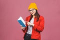 Beautiful young woman wearing casual and eyeglasses standing isolated over pink background, reading a book Royalty Free Stock Photo